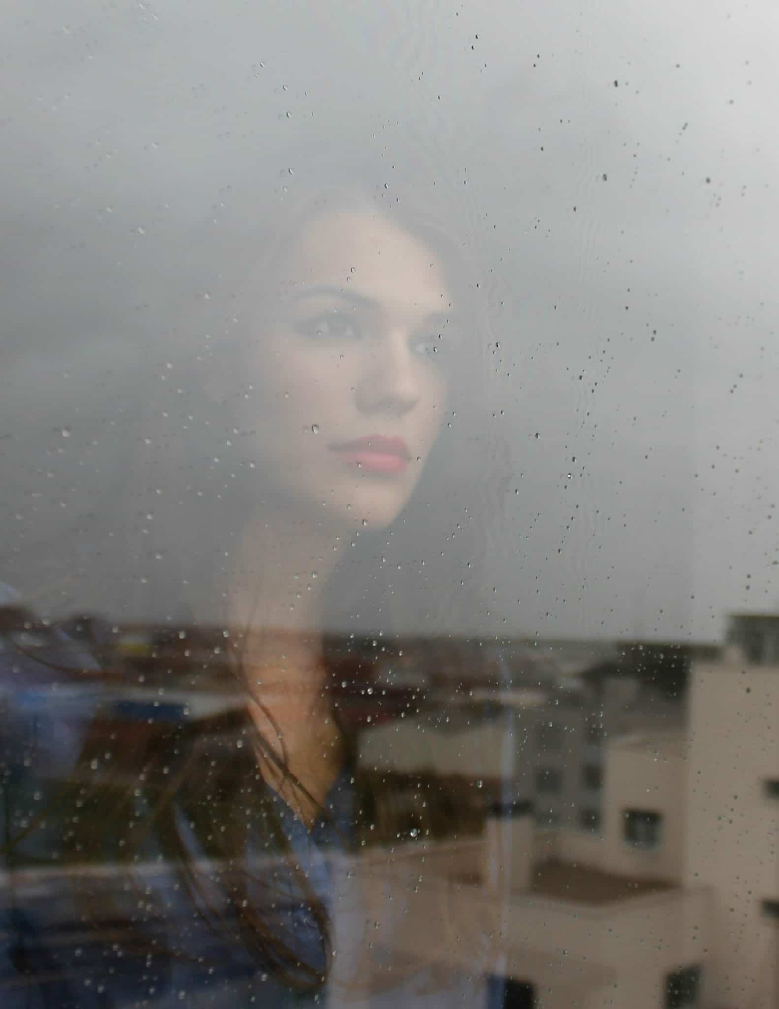 Beautiful woman in a bad marriage staring out through a rainy window