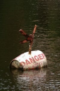 Old barrel with the word "Danger" floating in water signifying the danger of divorce without a lawyer