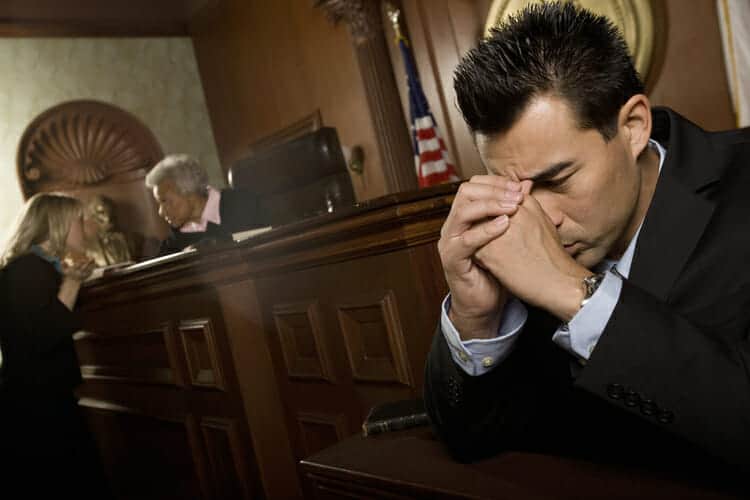 Upset man on the witness stand at his divorce court hearing while judge confers with lawyer