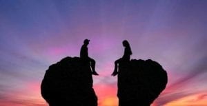 Divorcing sitting on rocks shaped as broken heart signifying amicable divorce.