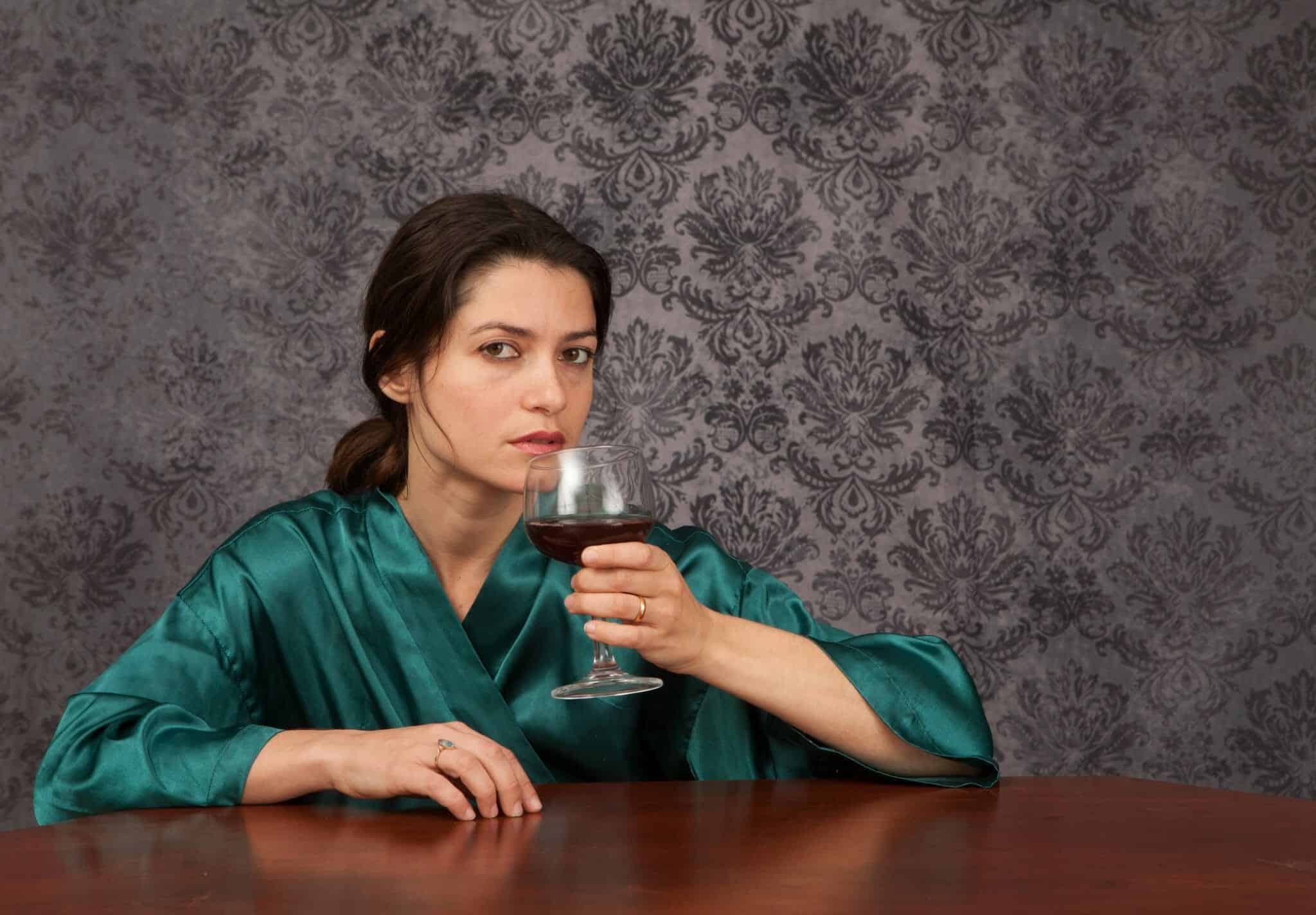 Woman looking at camera while drinking too much wine.
