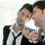Good-looking narcissist man looking lovingly at his reflection in the mirror.