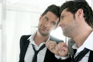 Good-looking narcissist man looking lovingly at his reflection in the mirror.