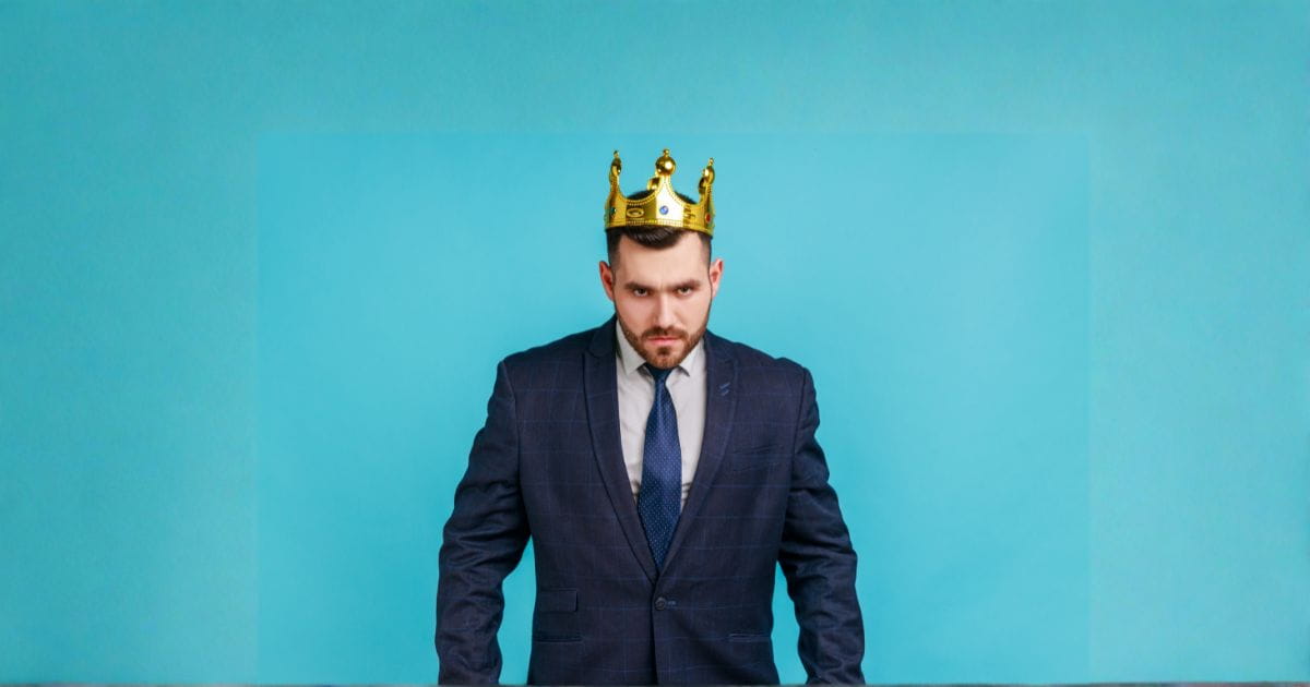 a narcissist Man in a suit looking angry and wearing a crown on his head