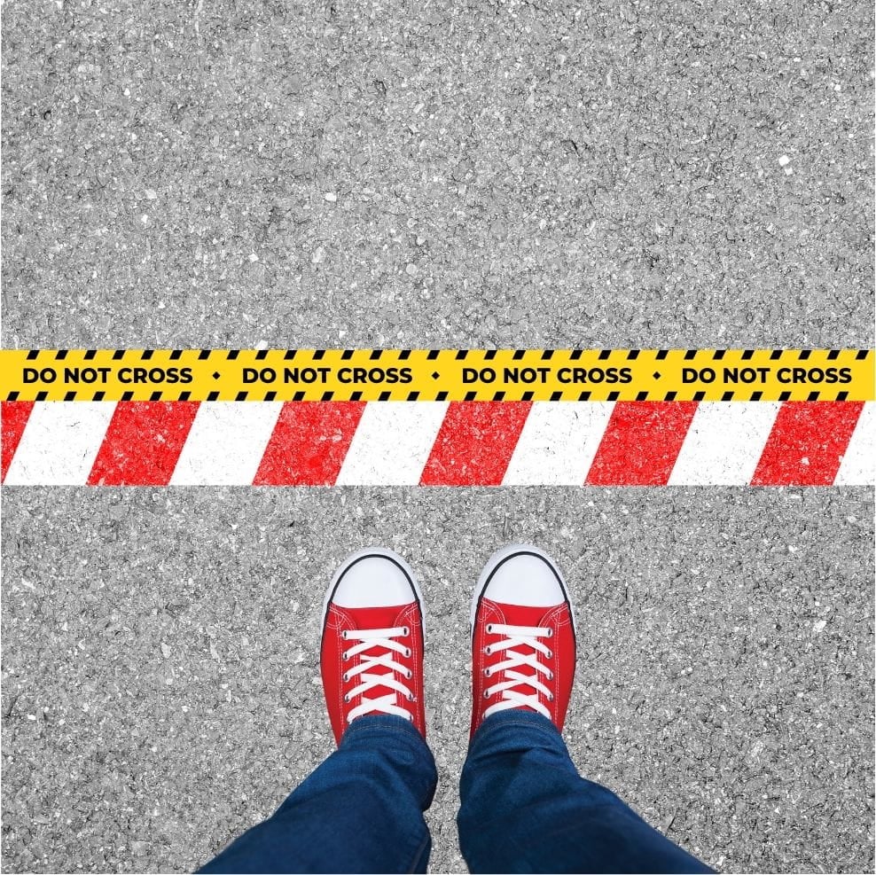 A pair of feet on the ground behind a line saying "Do Not Cross", symbolizing boundaries