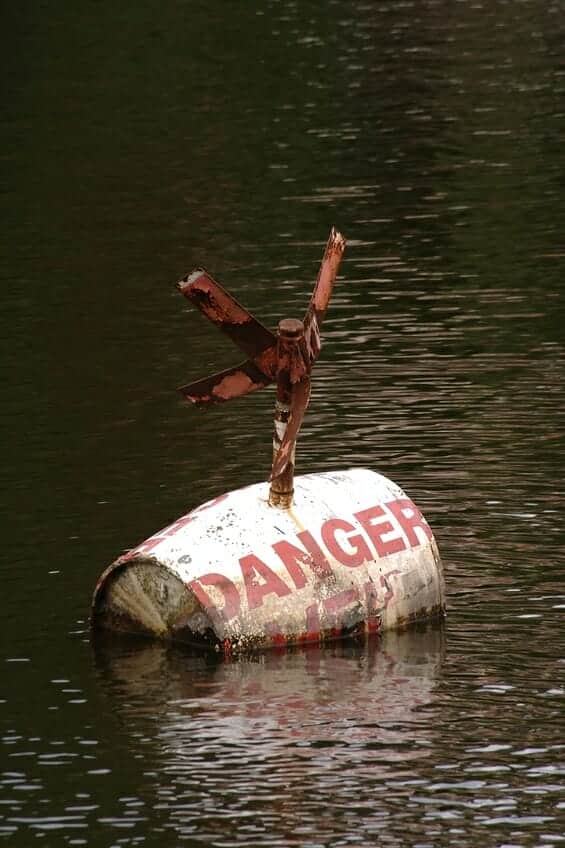Explosive barrel symbolizing the dangers of a cheap divorce floating in water with "Danger" painted on the barrel