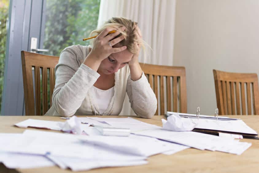 Upset woman looking at paperwork with her head inher hands