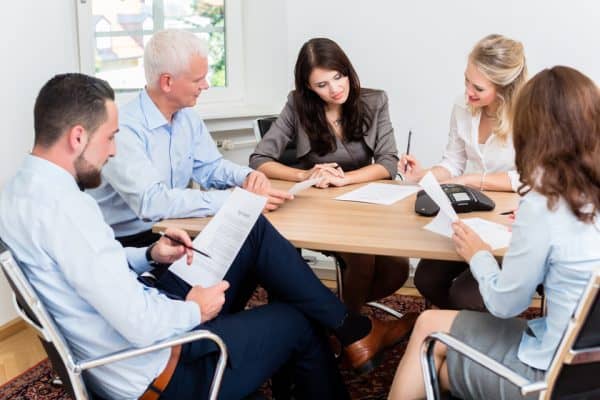 Couple and their lawyers sitting around a table using Collaborative Law to resolve their divorce.