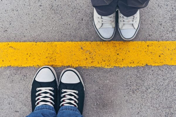 Divorce Mediation Two people toe to toe on a yellow line. Standoff in divorce mediation.