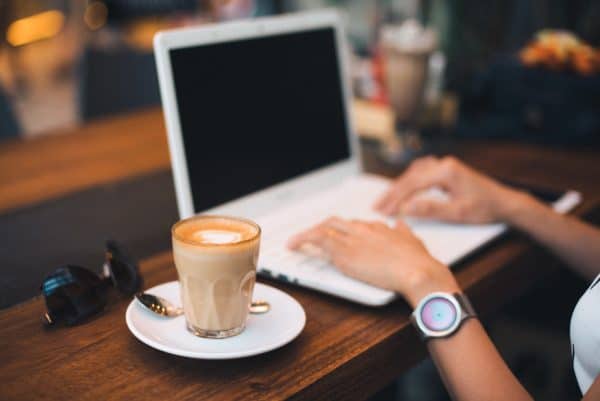 Hands of a woman working on laptop computer with a cup of coffee. Online support