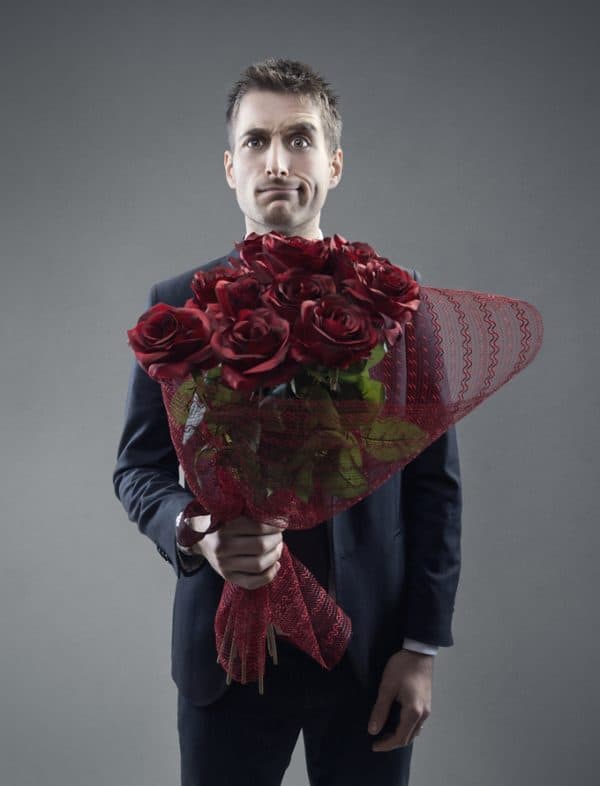 Man with exasperated smile holding a dozen roses. Don't date during divorce!