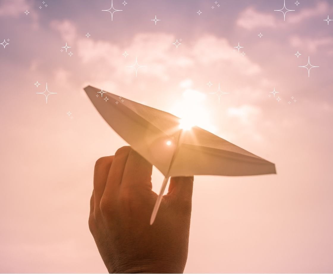dream life A hand holding a paper airplane and throwing it towards the sunset