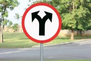 Sign with black arrows pointing in 2 different directions. Which way to go?