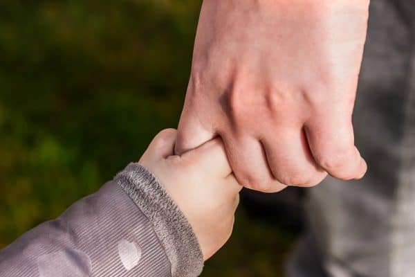 Close up of parent's hand holding a todler's hand. Parenting.