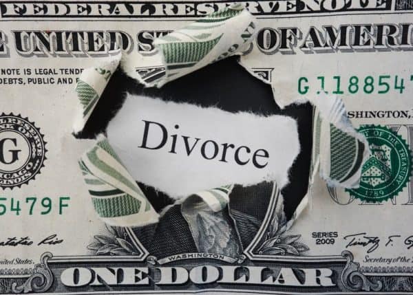 Close up of dollar bill with a whole torn in the middle and the word Divorce, signifying the cost of divorce.