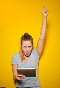 Woman hooting with her arm up in front of a bright yellow background! Time for a divorce party!