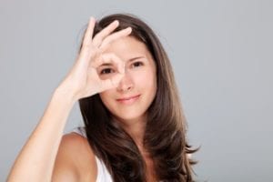 Woman looking through a circle made with her fingers demonstrating focus.