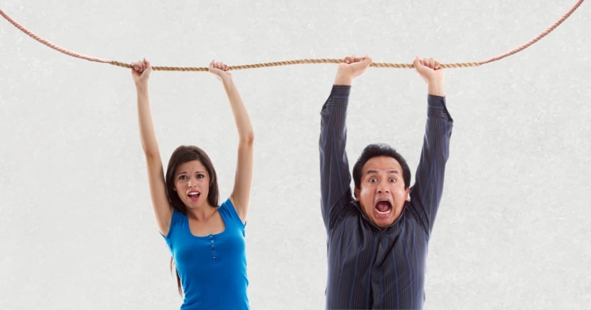 man and woman hanging on a rope, refusing to let go