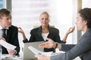 Female mediator using divorce mediation tips is meditating while two male lawyers argue.