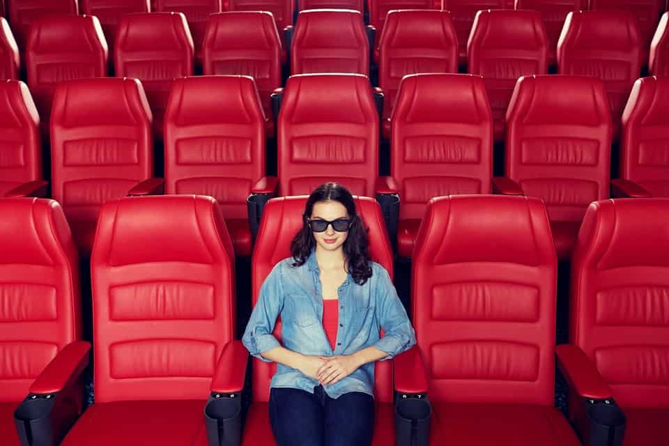 Woman alone on Valentine's Day sitting by herself in a movie theatre of red seats.