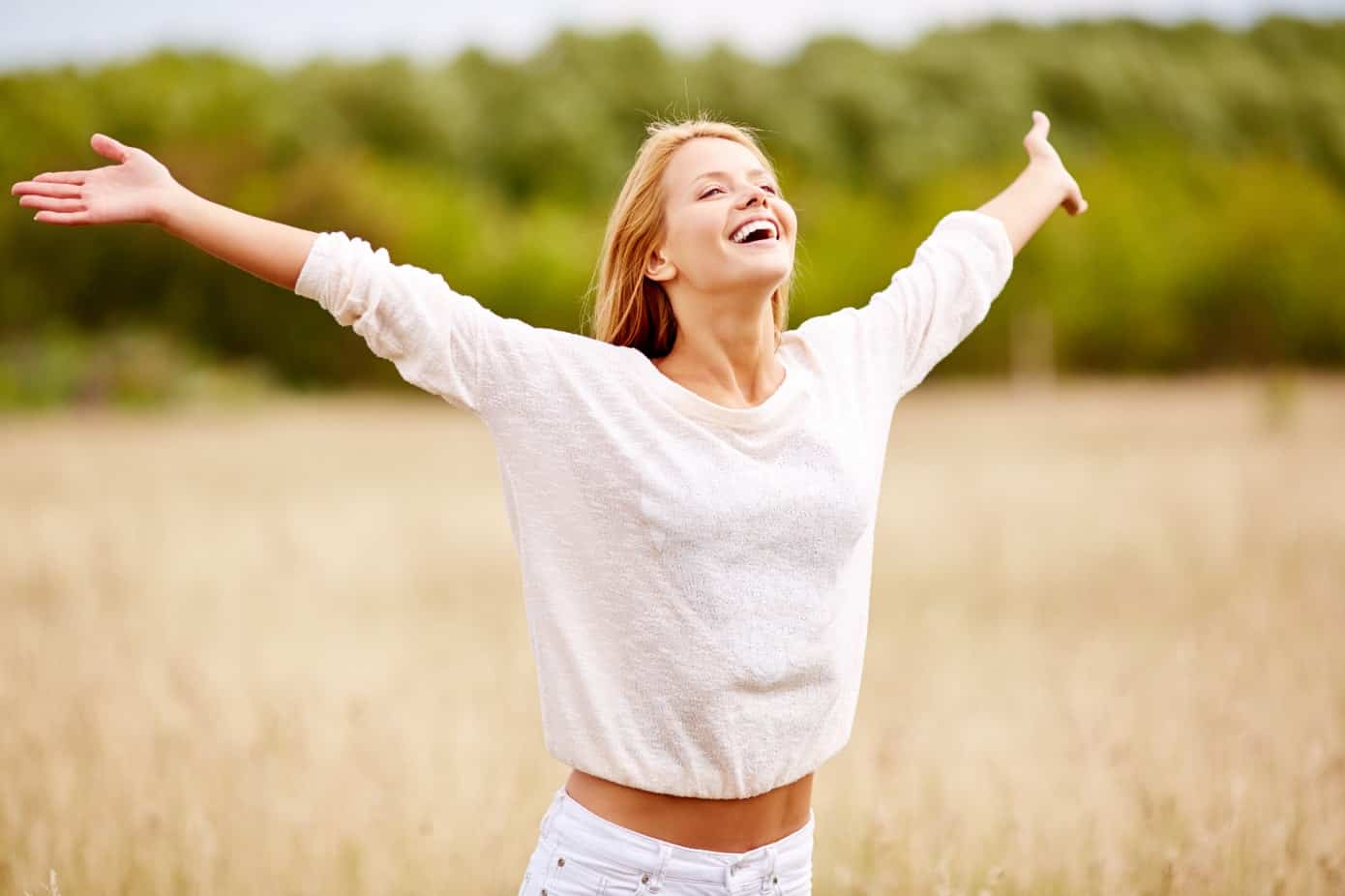 SMiling blonde woman with outstretched arms, as if to say, "Be happy!"