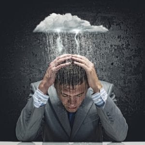 Depressed businessman dealing with divorce stigma has a rain cloud making a thunderstorm over his head.