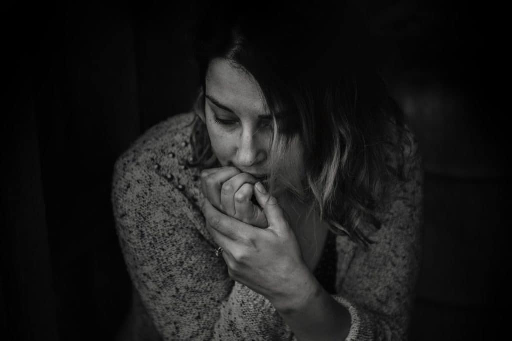 Black and white picture of a a woman with anxiety biting her nails.