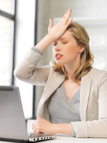 Woman at a laptop hitting her head with her hand in disbelief. Divorce and social media don't mix.