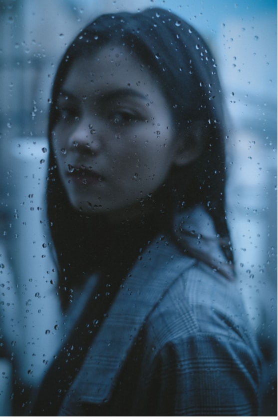 Beuatiful Asian woman looking through a rain-stained window.