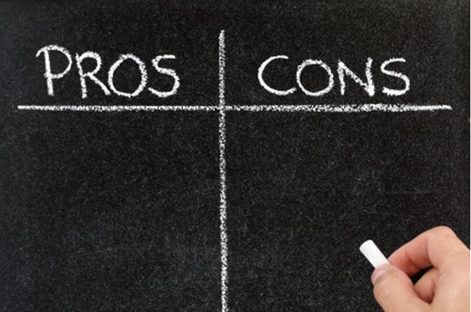 Blackboard with a hand writing "Pros and Cons" in white chalk