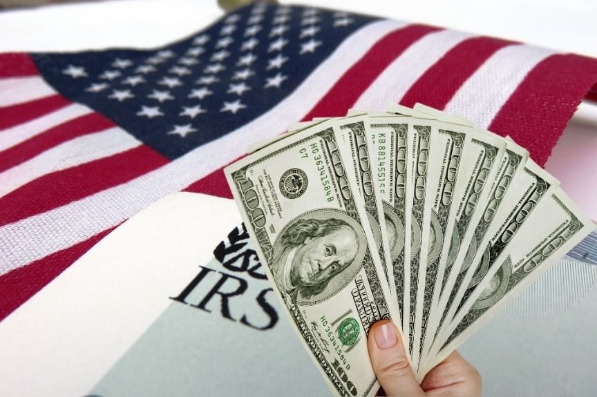 The US flag with an IRS envelope and a hand holding cash. divorce and taxes