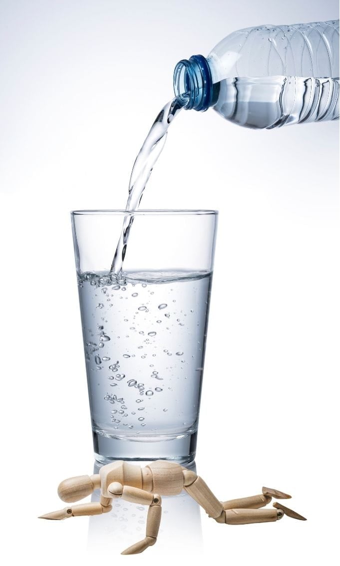 A humanoid doll on all fours, bearing a glass on its that has water continously poured into it. Capacity