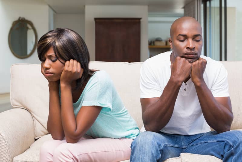 Upset African American couple deciding whether to divorce and sitting on a couch.