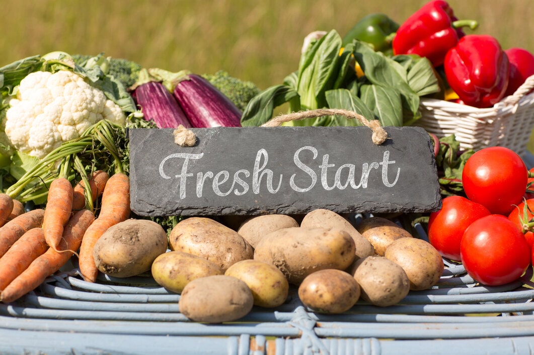 Fruits and vegetables at a farm stand withthe sign "Fresh Start" on them.
