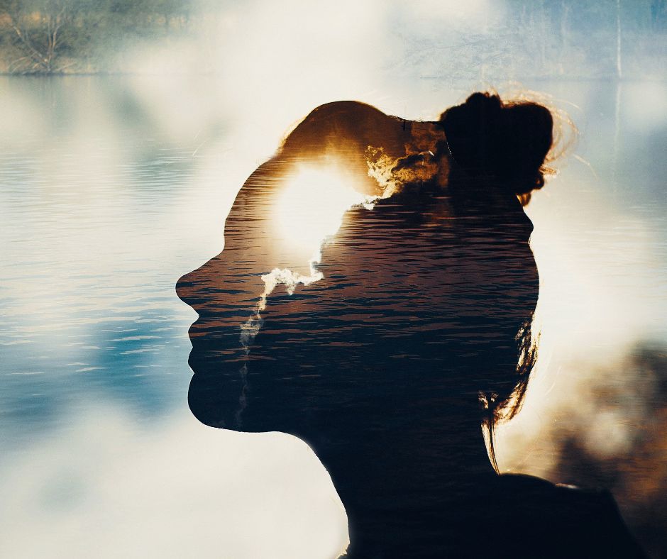 Silhouette of a woman's head with a burst of sunshine and clouds in her brain.