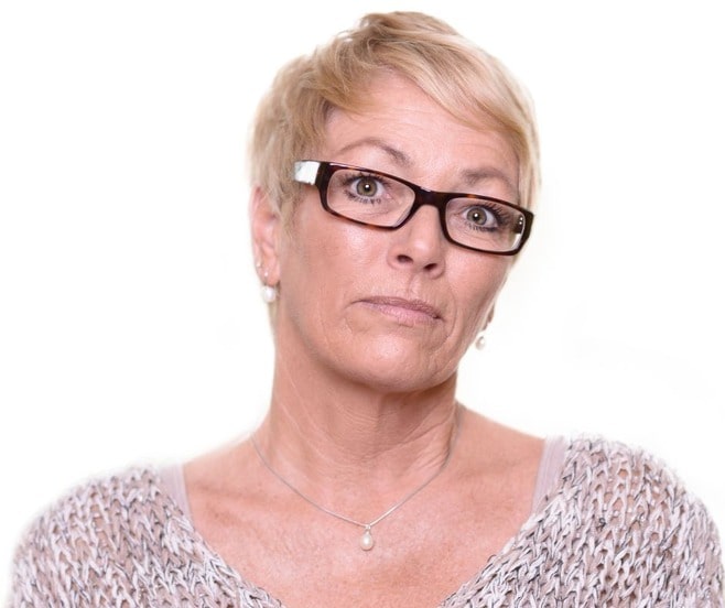 Tough looking middle-aged woman with short blonde hair and horn-rimmed glasses.