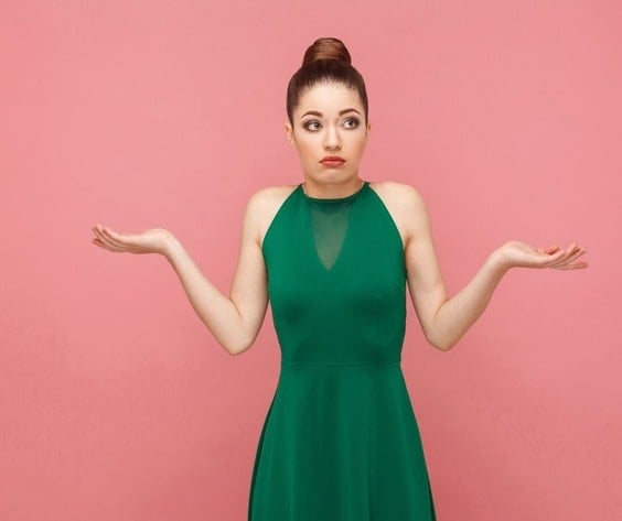 Beuatiful young woman on a pink background with her hands out and a look that says, "I don't care."