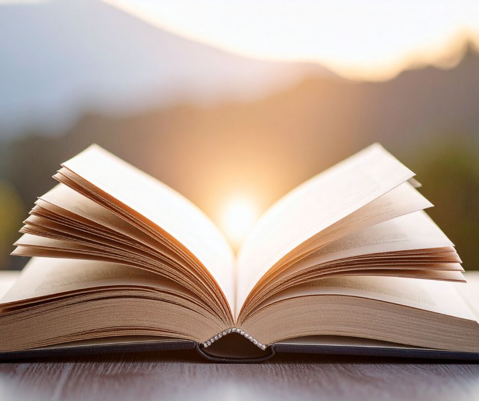 Between chapters Open book with cunrise in the mountains behind it signifying between chapters.