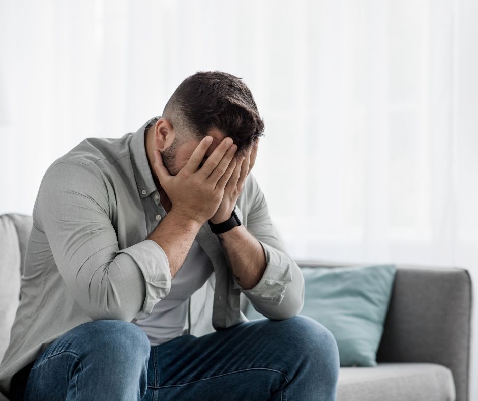 Shame Man sitting on a couch with his hands over his face. Shame.