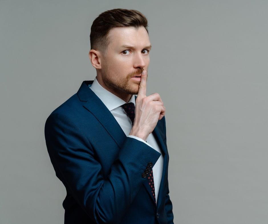 Motive Matters Secretive businessman with finger to his lips. Motive Matters