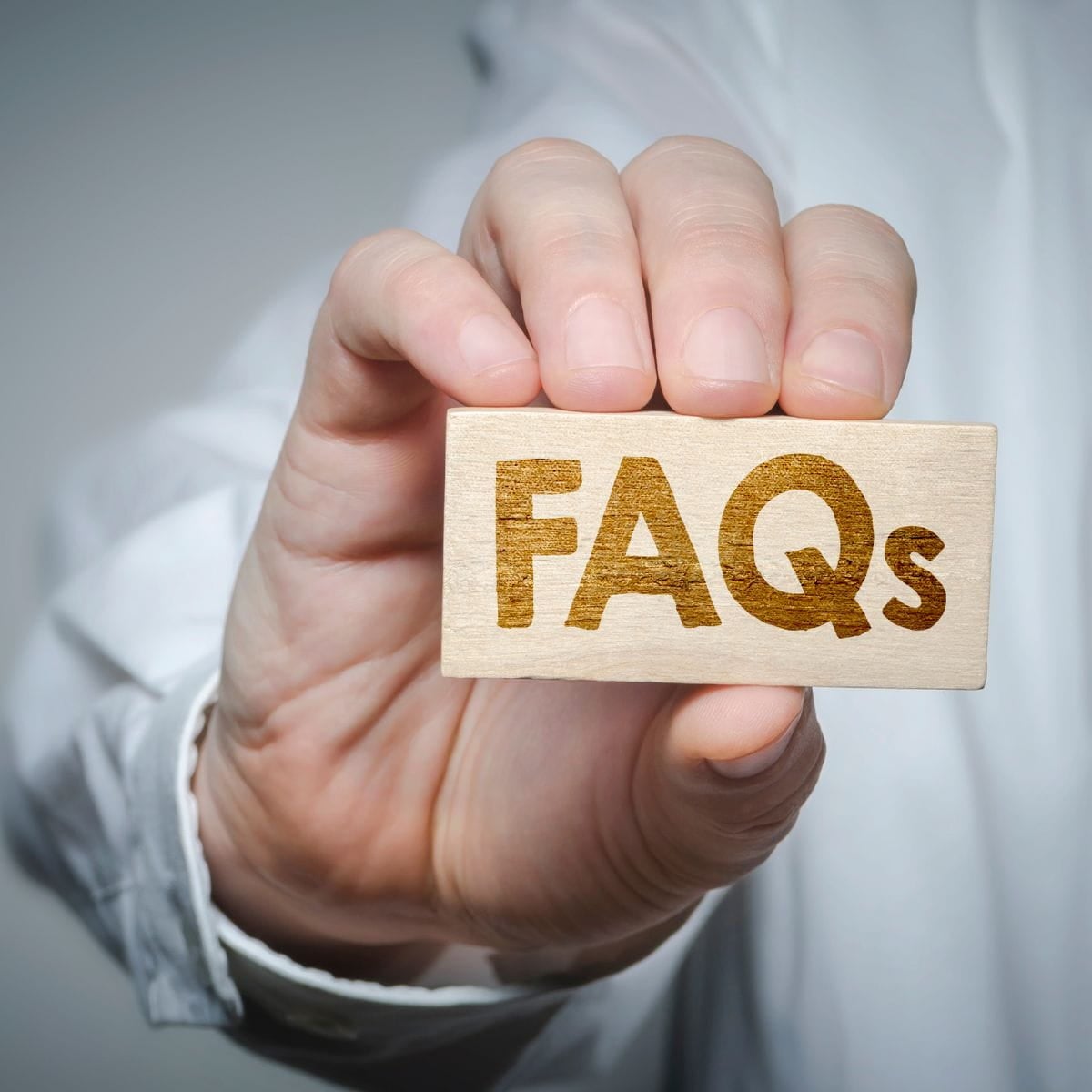 Divorce Lawyer FAQs Close up of a man's hand holding a sign that says "FAQs" Divorce lawyer FAQs.