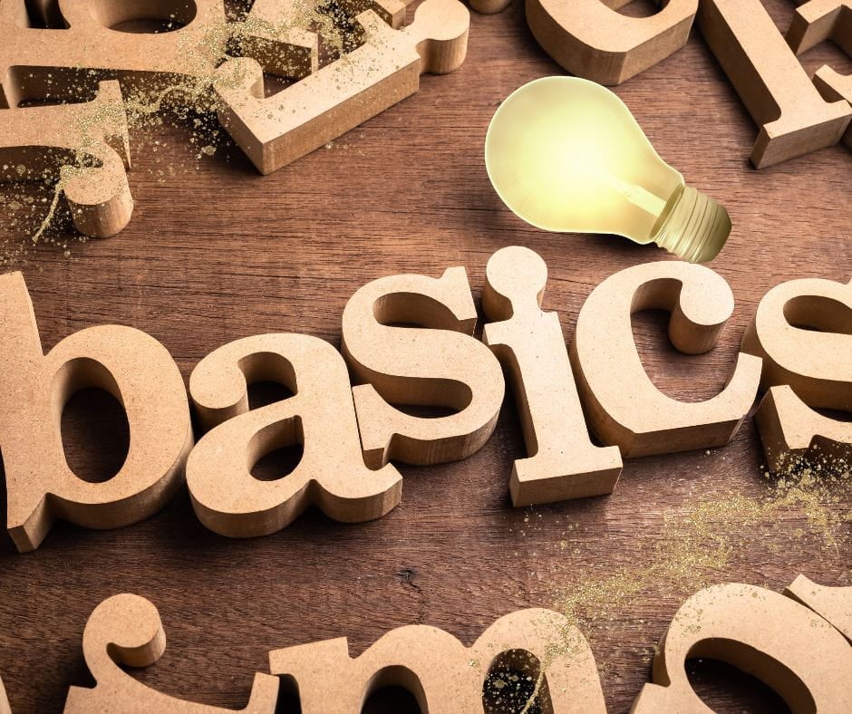 Basics Wood letters spelling "Basics" with golden light bulb on them.