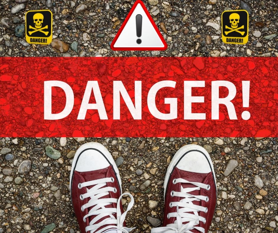 Red tennis shoes standing at a Bright red line that says "Danger!" with warning signs.