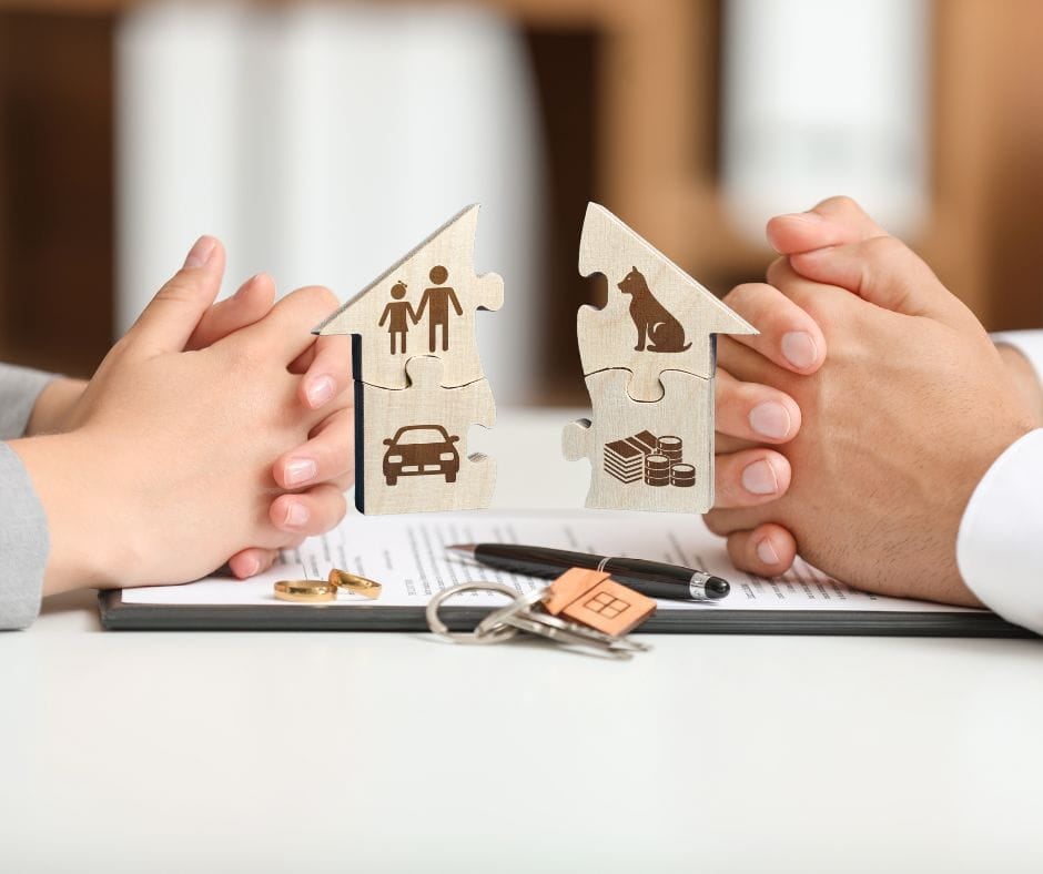 Hands of a woman and man who are dividing property in a divorce facing each other with an agreement, keys, edding rings etc between them.