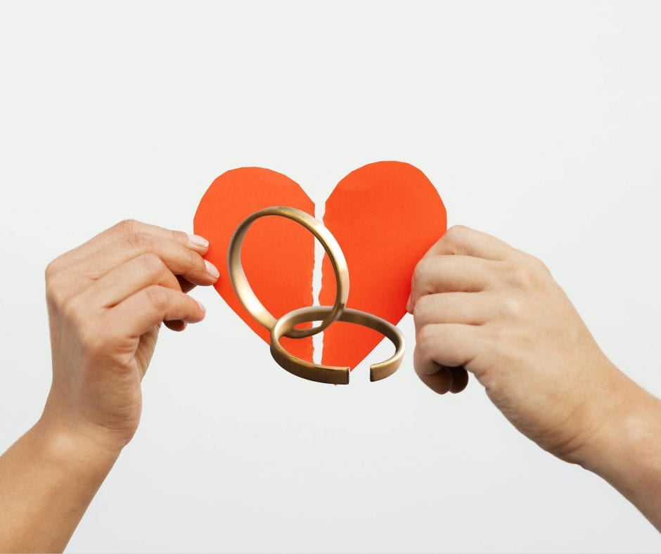 Two hands pulling a broken heart with broken wedding rings on top. Legal Separation.