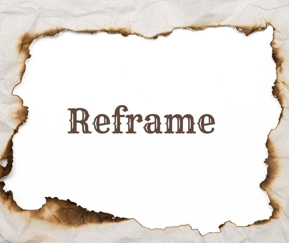 Piece of paper with a rectangle burned through the middle making a reframe of the way you see life. Word Reframe in the middle.