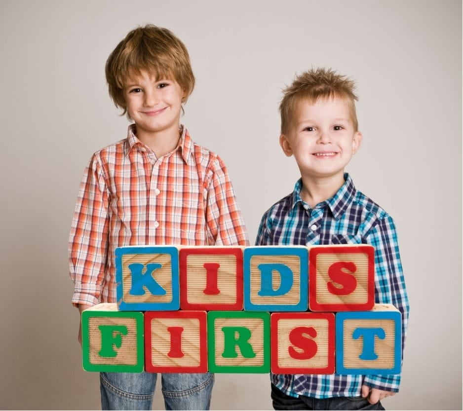 Two young boys smiling and colored blocks saying "Kids First"