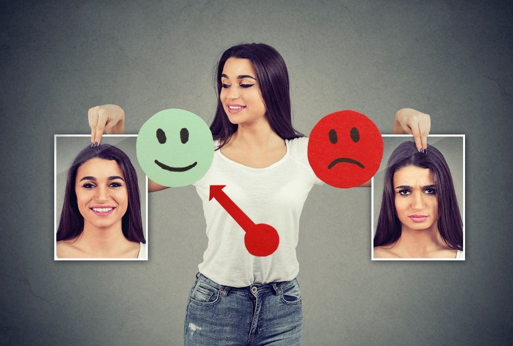 Woman holding up photos of herself in different moods, representing mood swings