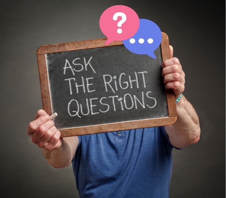 A person holding up a sign that says "Ask the right questions"