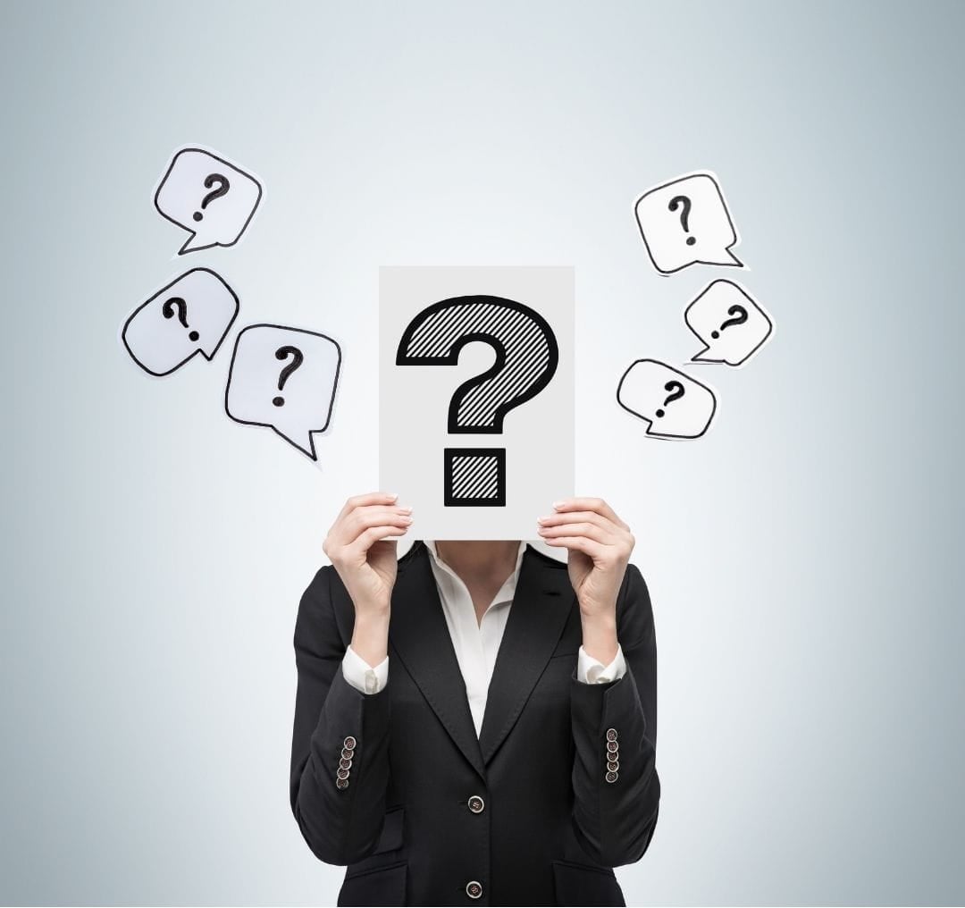 A person holding up a huge question mark sign in front of their face